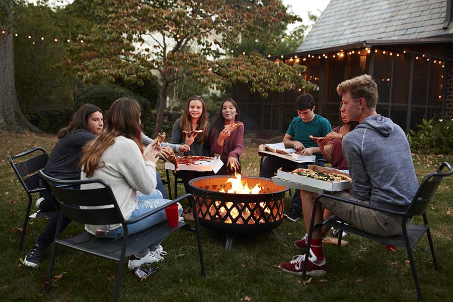 Friends enjoying pizza around a firepit in winter